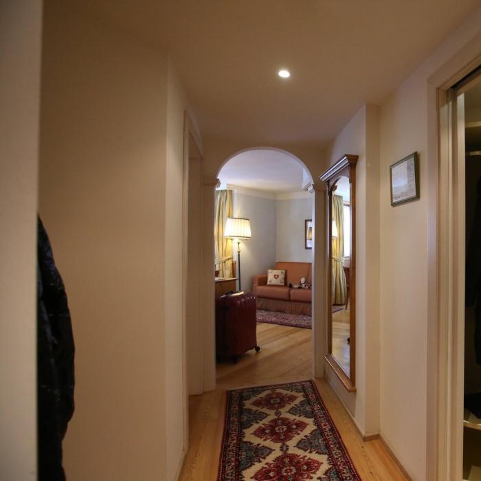 Warm, cozy hallway with colorful rug and soft lighting.