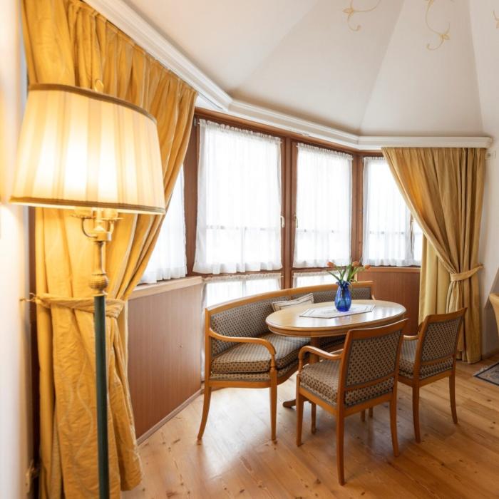 Elegant living room with table, chairs, and golden curtains, warm and cozy atmosphere.