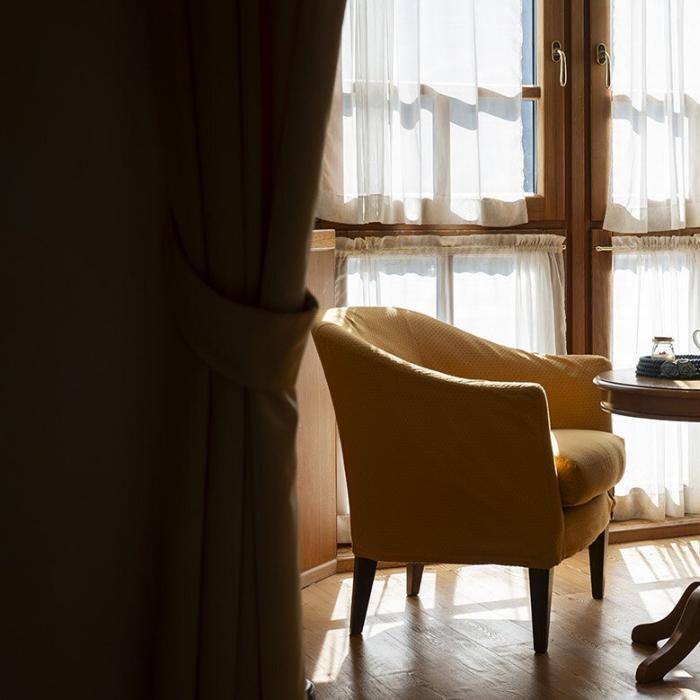 Woman in robe reads peacefully by a bright window.