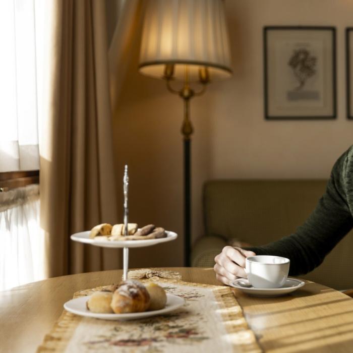 Thoughtful man sips coffee beside pastries in a warm, cozy setting.