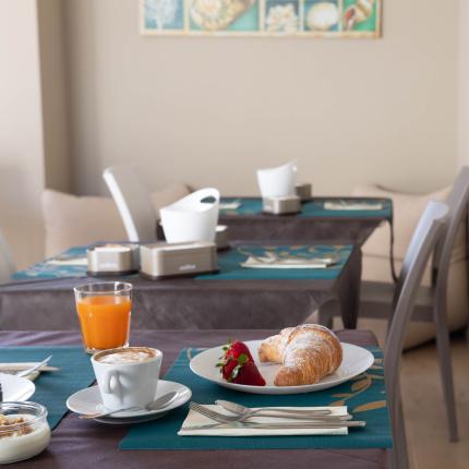 Frühstück mit Croissant, Saft und Cappuccino in gemütlicher Atmosphäre.