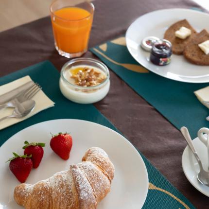 Frühstück mit Croissant, Erdbeeren und Orangensaft.