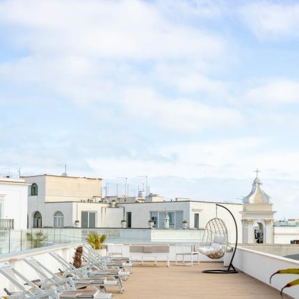 Terrasse mit Liegestühlen und Hängesessel, Blick auf Dächer.