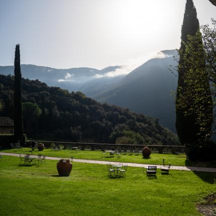 Paesaggio collinare con prato verde e cipressi sotto il sole.