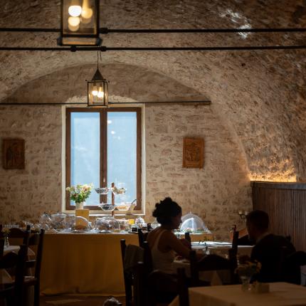 Interno rustico con tavolo imbandito e persone sedute.