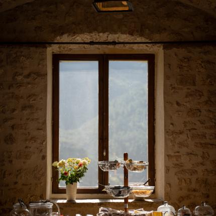 Tavolo colazione con dolci, fiori e vista montagna.