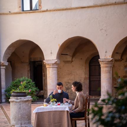 Due persone che fanno colazione in un cortile storico.