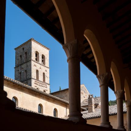 Campanile romanico visto da un chiostro con archi.