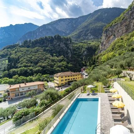 Piscina con vista su montagne verdi e cielo azzurro, atmosfera serena e rilassante.