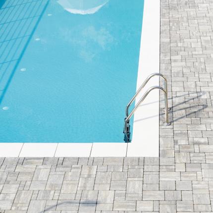 Piscina luminosa, lettini ordinati, atmosfera di relax e tranquillità estiva.