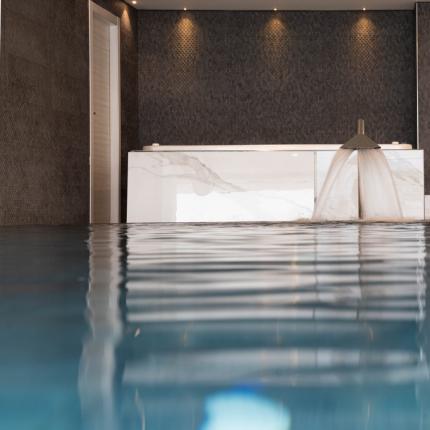 Piscina interna elegante con cascata d'acqua, atmosfera rilassante e moderna.