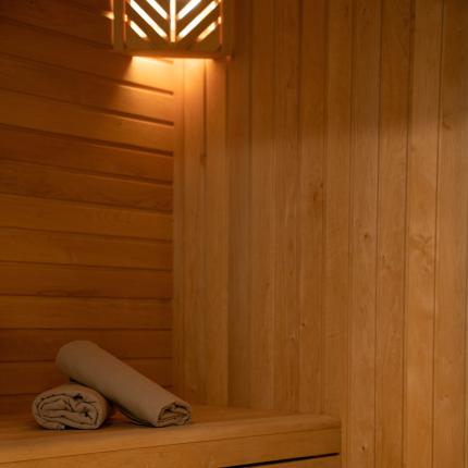 Una sauna accogliente con luci soffuse, secchio di legno e asciugamani ordinati.