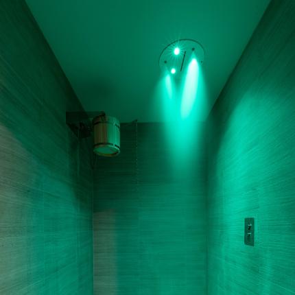 Doccia emozionale con luci verdi e pavimento a ciottoli, atmosfera rilassante.