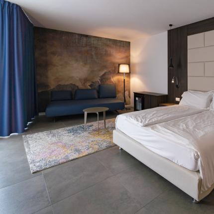 Camera elegante con letto matrimoniale e divano, atmosfera accogliente e moderna.
