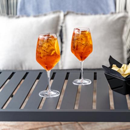 Due spritz arancioni su tavolo con patatine, atmosfera rilassante.