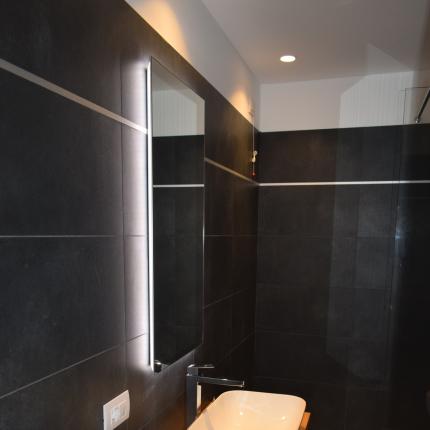 Bagno moderno, elegante e minimalista con pareti scure e lavabo bianco.