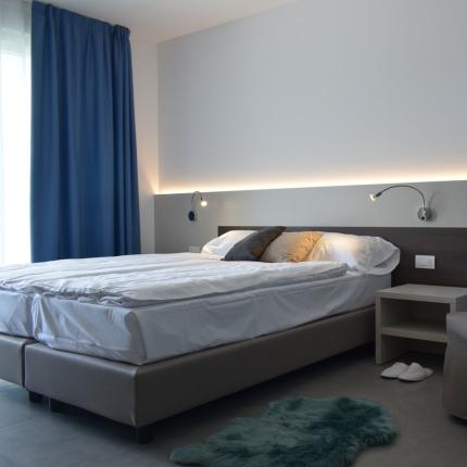 Camera moderna, letto comodo, toni blu e grigi, atmosfera rilassante e accogliente.