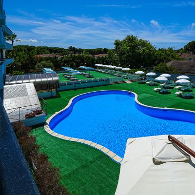 Piscina all'aperto con lettini e ombrelloni, cielo azzurro.