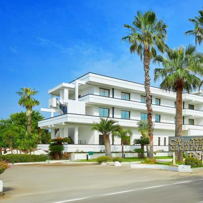 Hotel moderno con palme, cielo azzurro e strada.