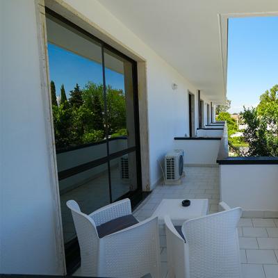 Balcone moderno con sedie bianche, vista su alberi verdi.