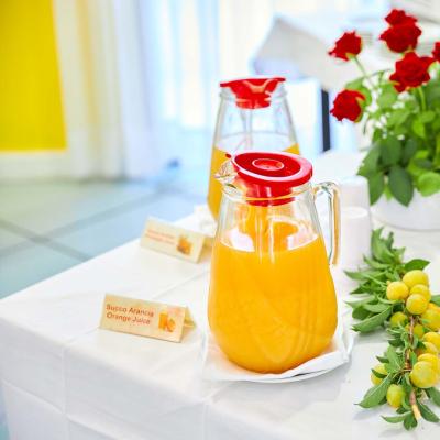 Caraffe di succo con fiori e frutta su tavolo decorato.