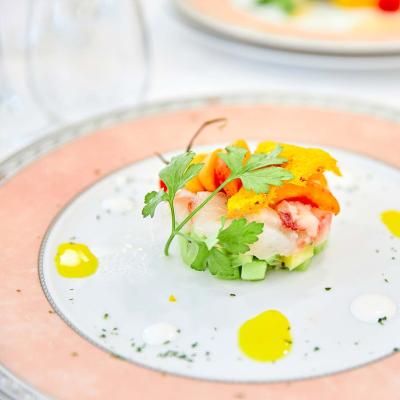 Piatto gourmet con pesce, verdure e decorazioni colorate.