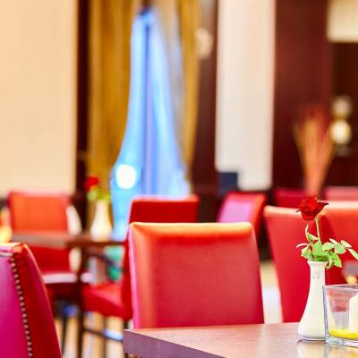 Sala da pranzo elegante con sedie rosse e rose sui tavoli.