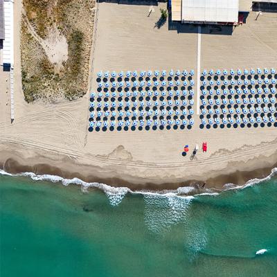 Vista aerea di una spiaggia con ombrelloni ordinati.