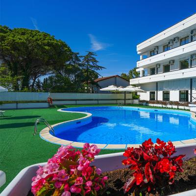 Piscina all'aperto con fiori, edificio moderno sullo sfondo.