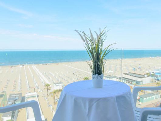 Sea view with beach, white table, and plant, relaxing atmosphere.