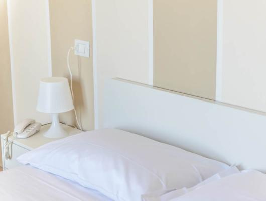 Cozy room with white bed, lamp, and phone.