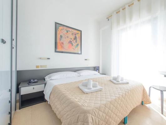 Bright room, double bed, abstract art, cozy and serene atmosphere.