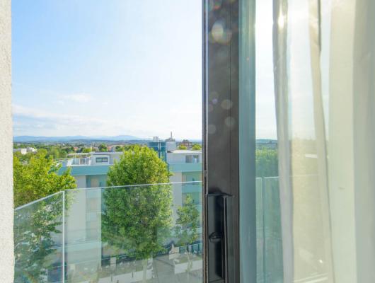 Bright view from an open window over city and distant mountains.
