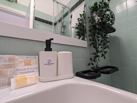 Elegant bathroom with green tiles, scented soaps, and decorative plant.
