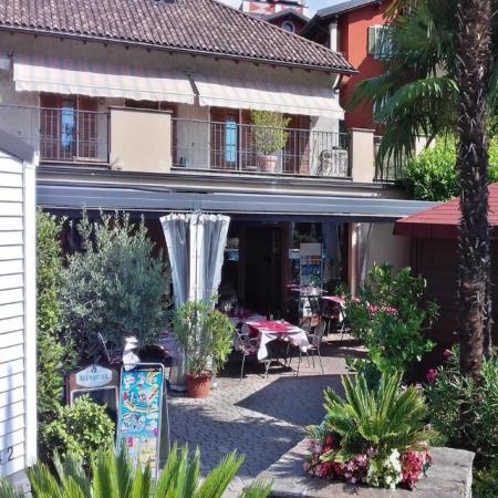 Giardino con palme e ristorante all'aperto in una giornata soleggiata.