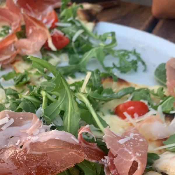 Pizza con rucola, prosciutto crudo, pomodorini e scaglie di parmigiano.