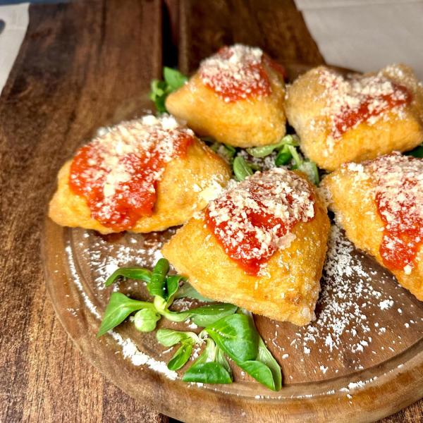 Frittelle ripiene con salsa di pomodoro e formaggio grattugiato.