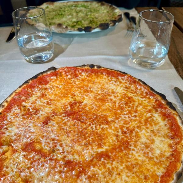 Due pizze sottili, una margherita e una con verdure, con bicchieri d'acqua.