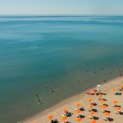 Spiaggia con ombrelloni arancioni e mare calmo.