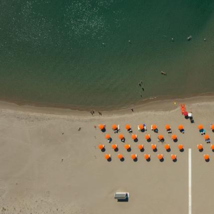 Spiaggia con ombrelloni arancioni e mare calmo.