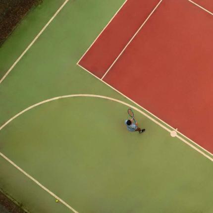 Vista dall'alto di un campo da tennis con giocatore.