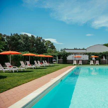 Piscina all'aperto con lettini e ombrelloni arancioni.