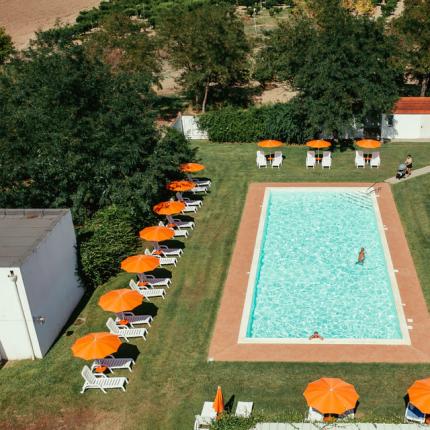 Piscina all'aperto con ombrelloni arancioni e lettini.