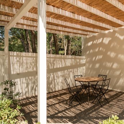 Terrazza con tavolo e sedie sotto pergolato, porta verde.