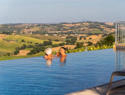 Due persone si rilassano in piscina con vista panoramica sulle colline.