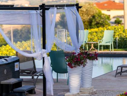 Piscina con gazebo decorato e sedie verdi in un ambiente tranquillo.