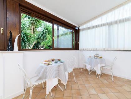 Bright breakfast room with set tables and large windows.