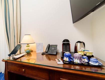 Desk with phone, lamp, coffee machine, and colorful cups.