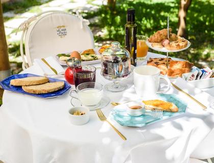 Outdoor breakfast with bread, pastries, and drinks.