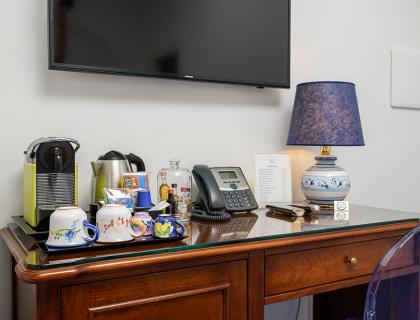 Desk with coffee machine, lamp, phone, and colorful cups.